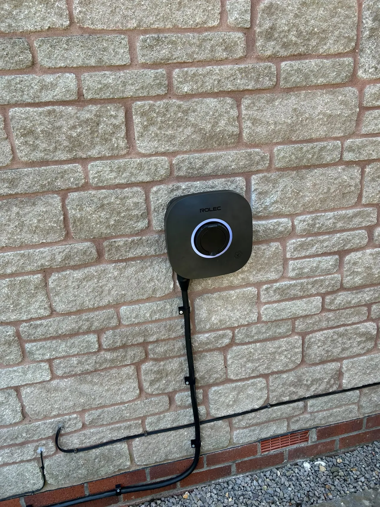 Wall-mounted home EV charging point installed on a stone-faced wall