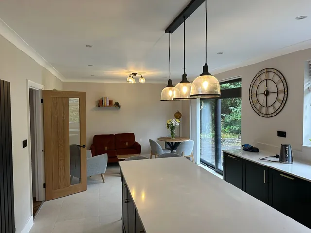 Open-plan kitchen and living area with industrial-style pendant lights and ceiling downlights