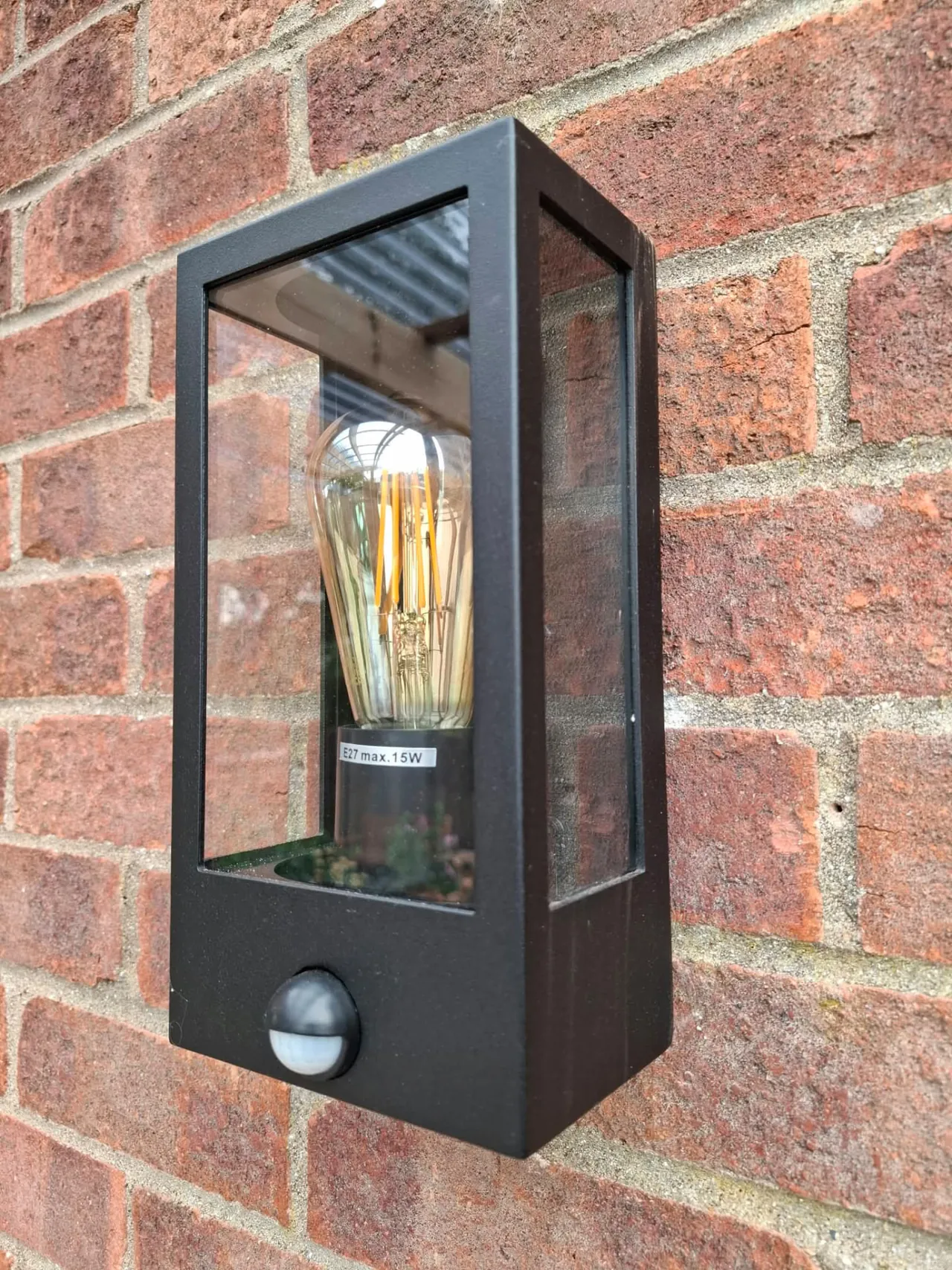 Outdoor wall lantern with PIR sensor installed on a brick wall
