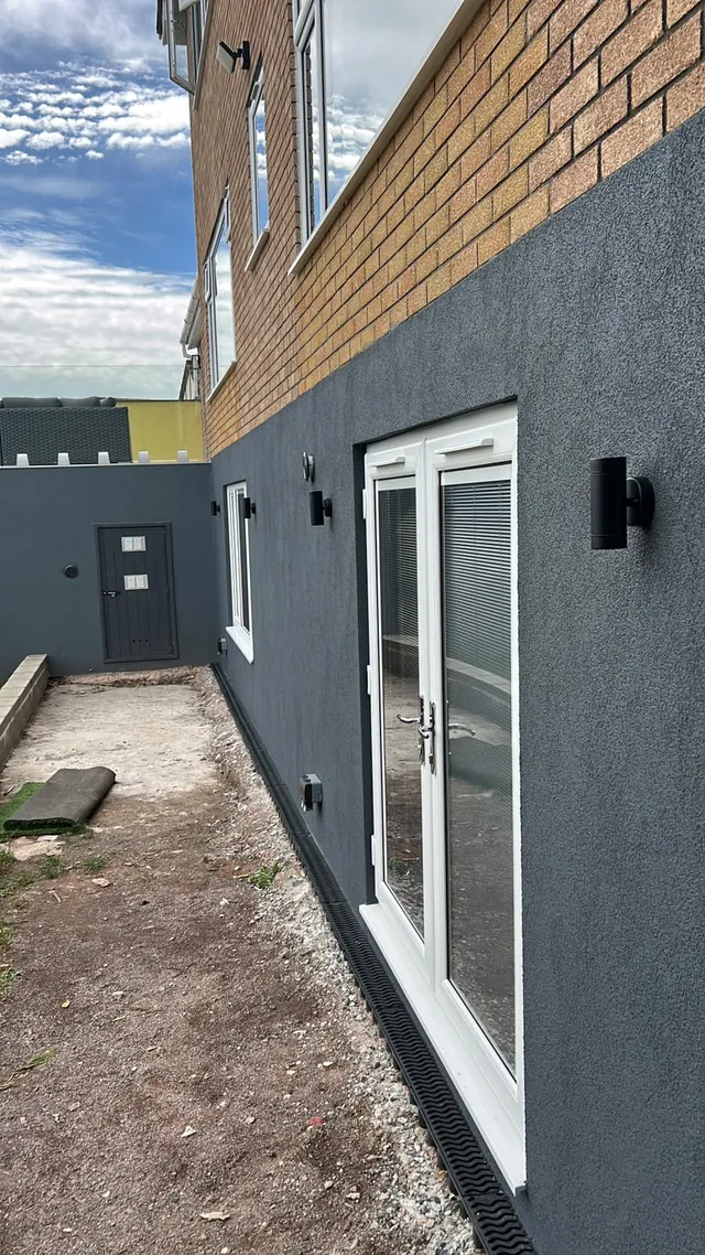 Black exterior wall lights installed along a rendered house wall