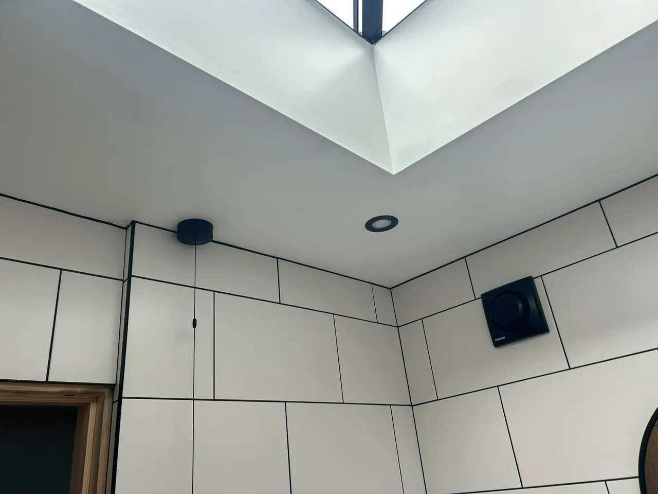 Wall-mounted bathroom extractor fan installed under a roof lantern