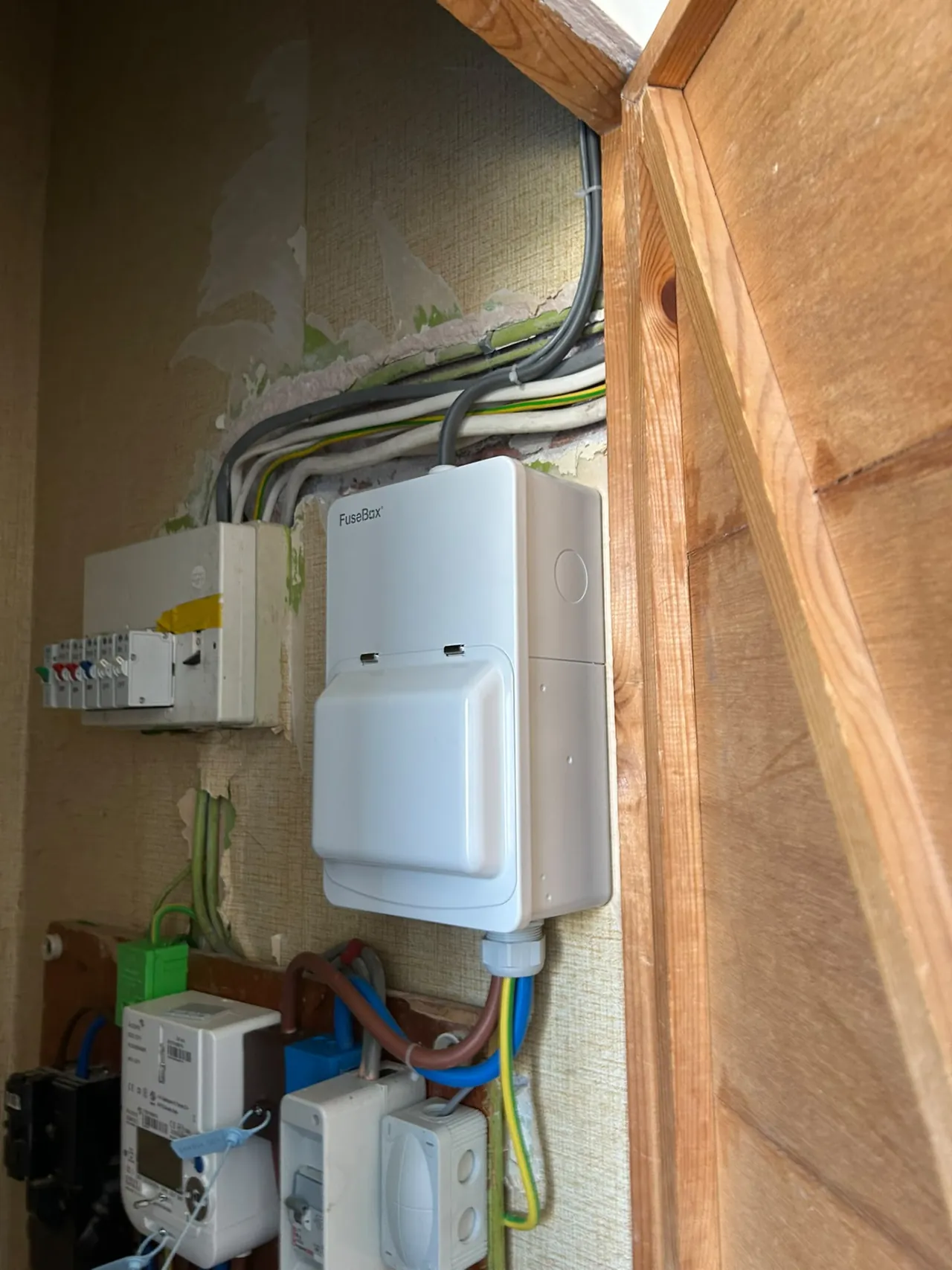 Consumer unit upgrade in progress with new board and meter beside exposed wiring