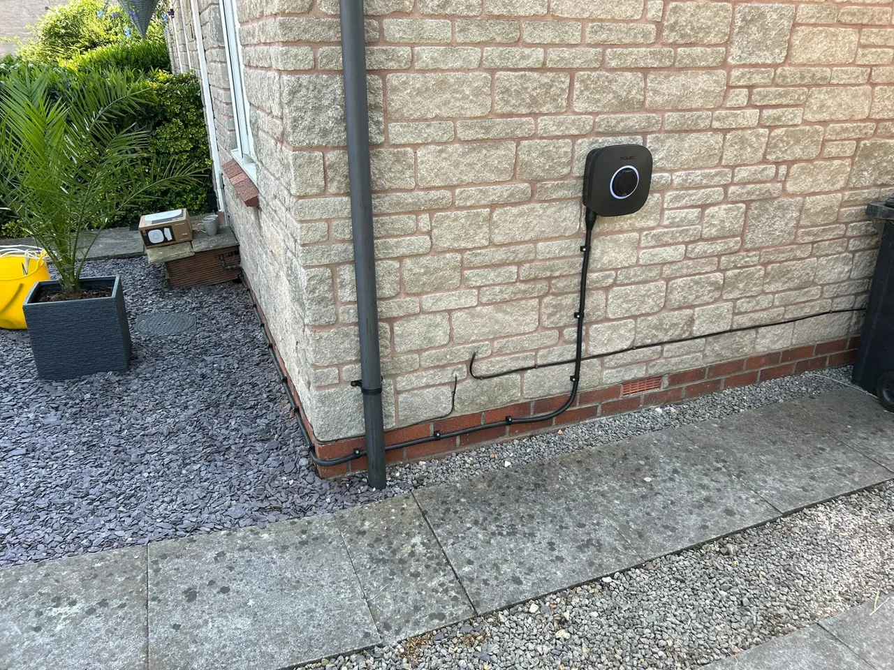 Home EV charger installed on an exterior house wall with neatly clipped cable