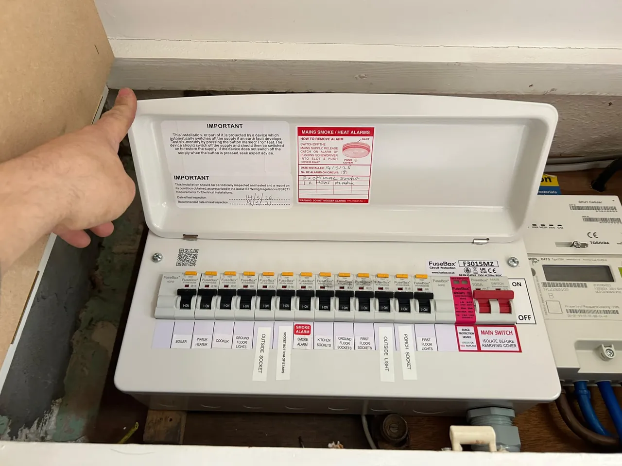 Electrician completing a new fully labelled consumer unit upgrade beside the electricity meter