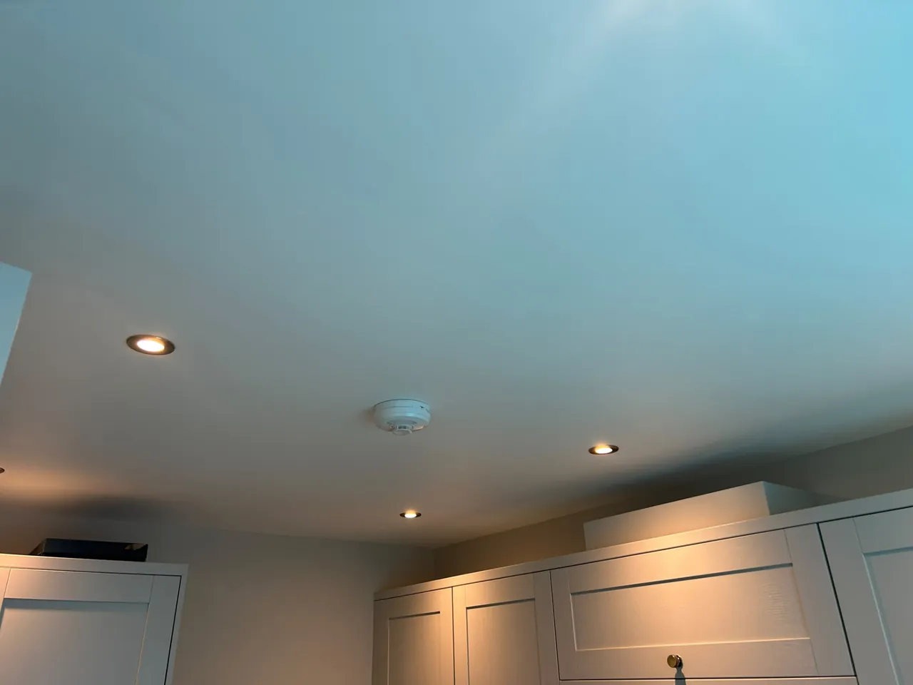 Ceiling-mounted smoke alarm installed alongside LED downlights in a kitchen